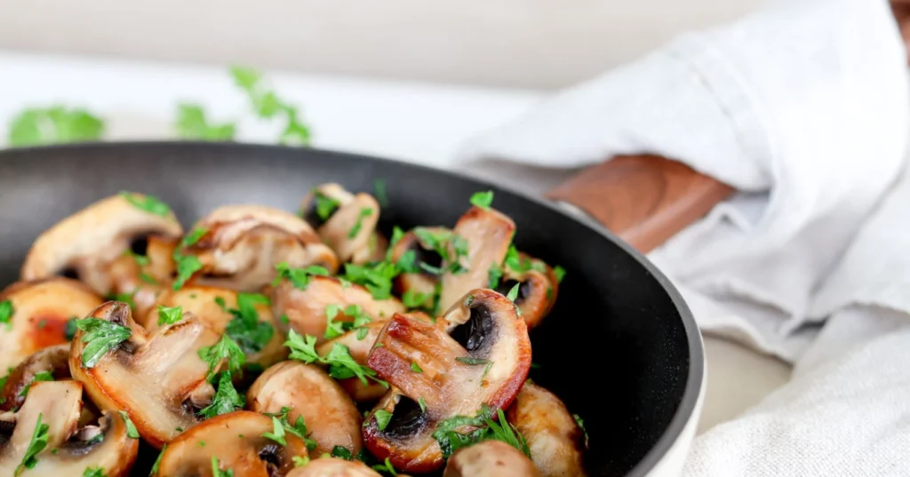 Paistettuja herkkusieniä pannulla persiljan kera.