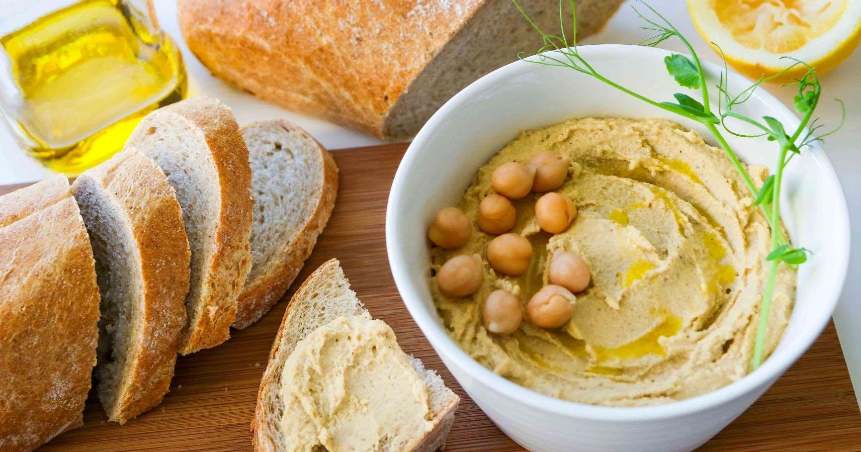 Hummus kulhossa tuoreen leivän kera.