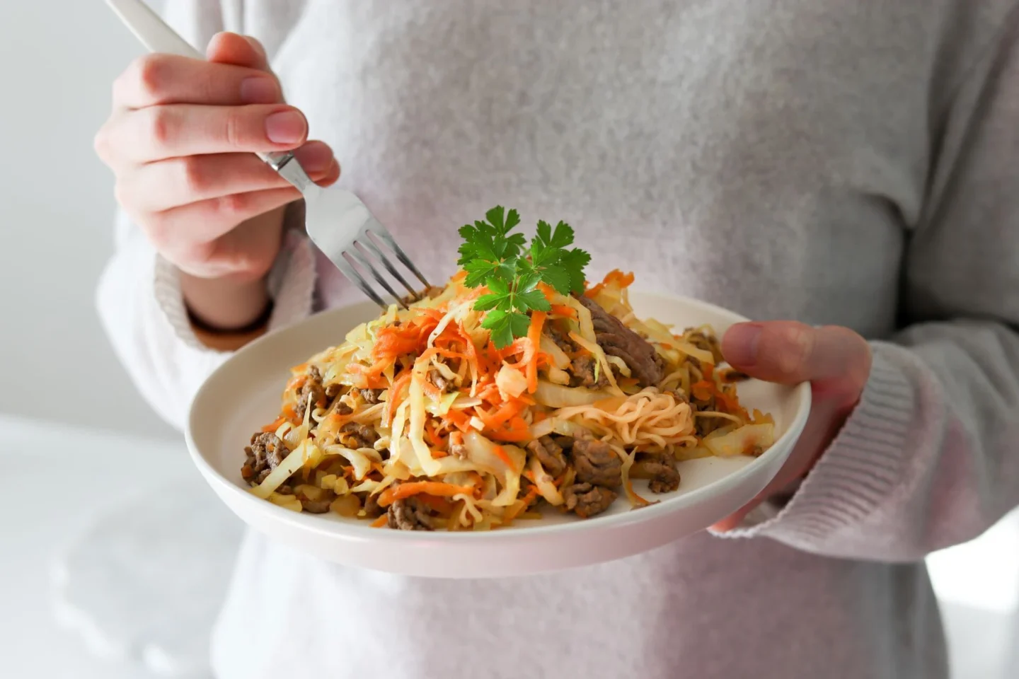 Jauheliha-nuudelipannu, jota ollaan jo syömässä lautaselta.