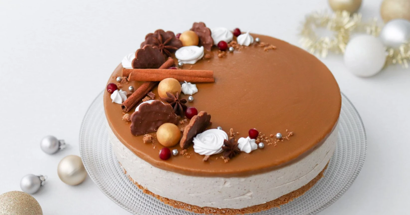 Jouluinen juustokakku kinuskikiilteellä ja joulukoristeita.