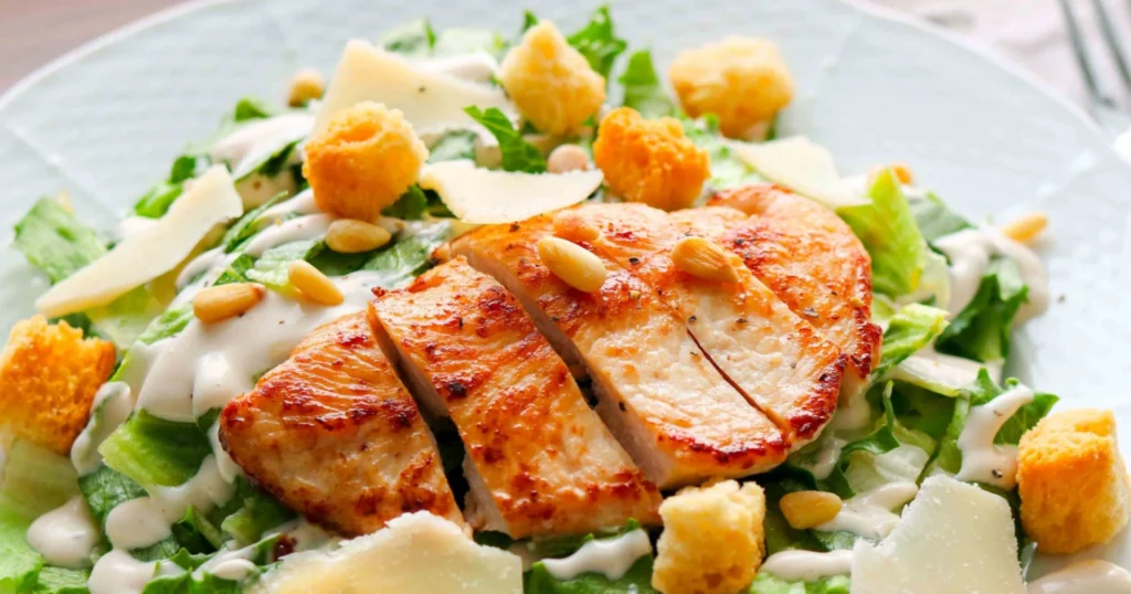 Kana-caesarsalaatti, jonka päällä on paistettu ja viipaloitu broilerin file.