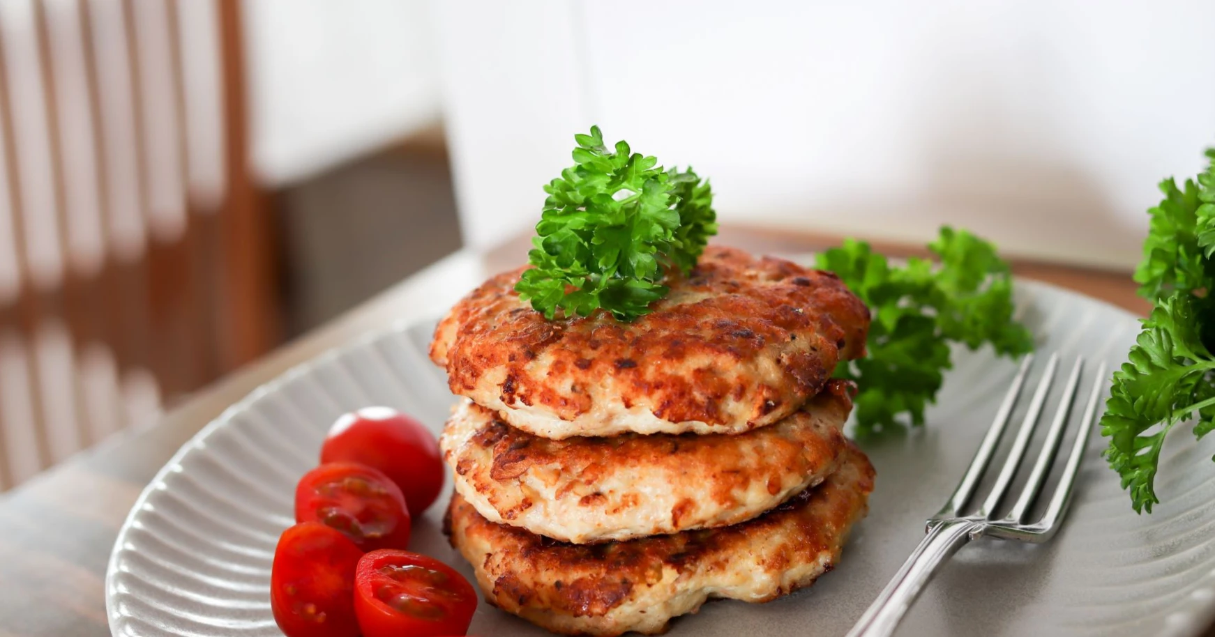 Kana-kantarellipihvejä sekä pieniä puolitettuja tomaatteja lautasella.