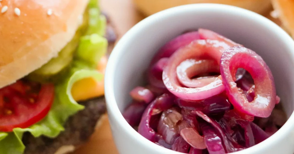 Karamellisoitu sipuli hampurilaisen vieressä kulhossa.