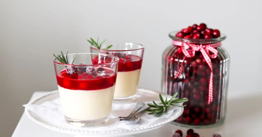 Karpalopannacotta, jonka pinnalla on tuoreita karpaloita ja rosmariinia.