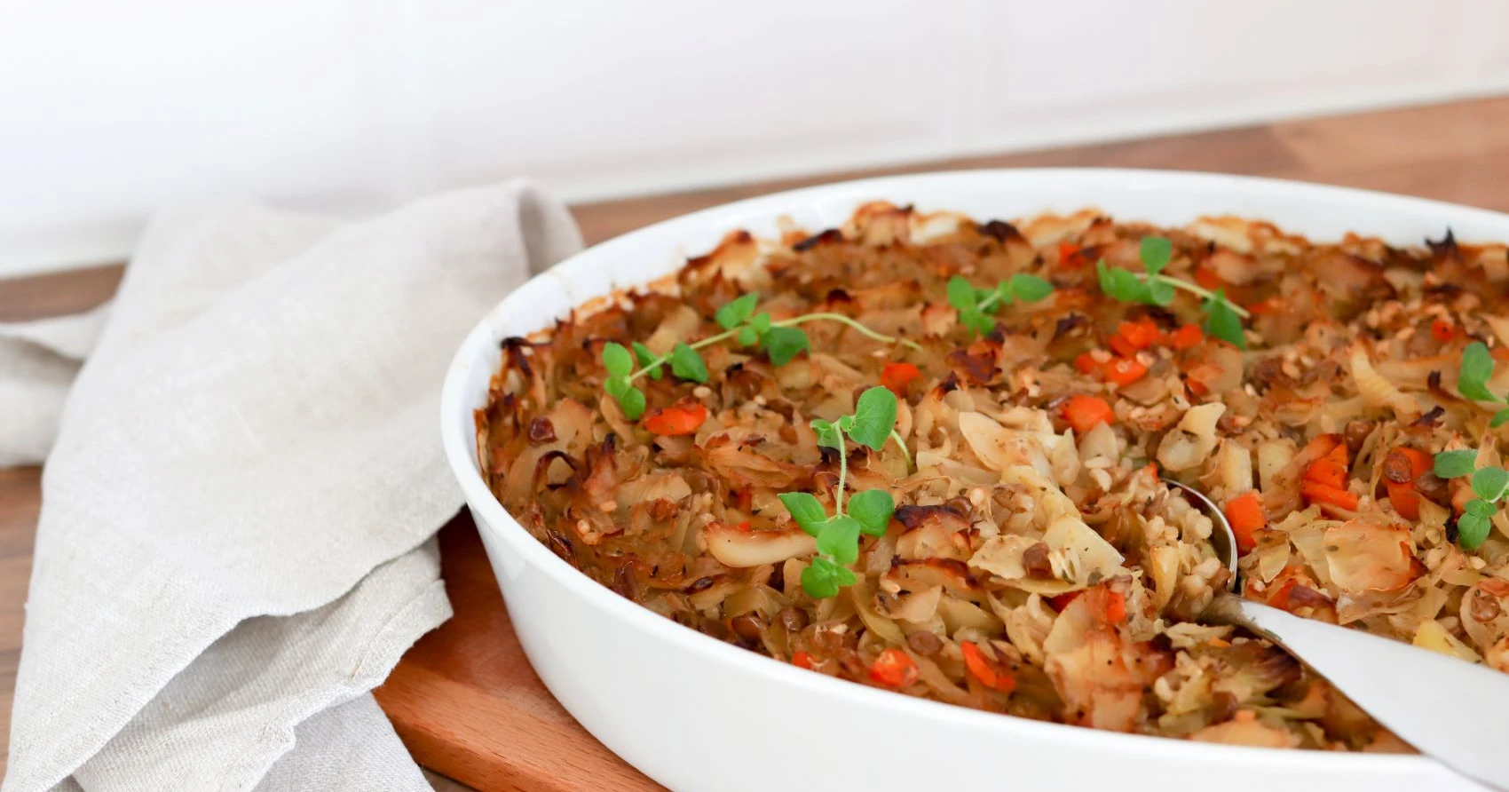 Kasvis-kaalilaatikkoa uunivuoassa tuoreella oreganolla koristeltuna.