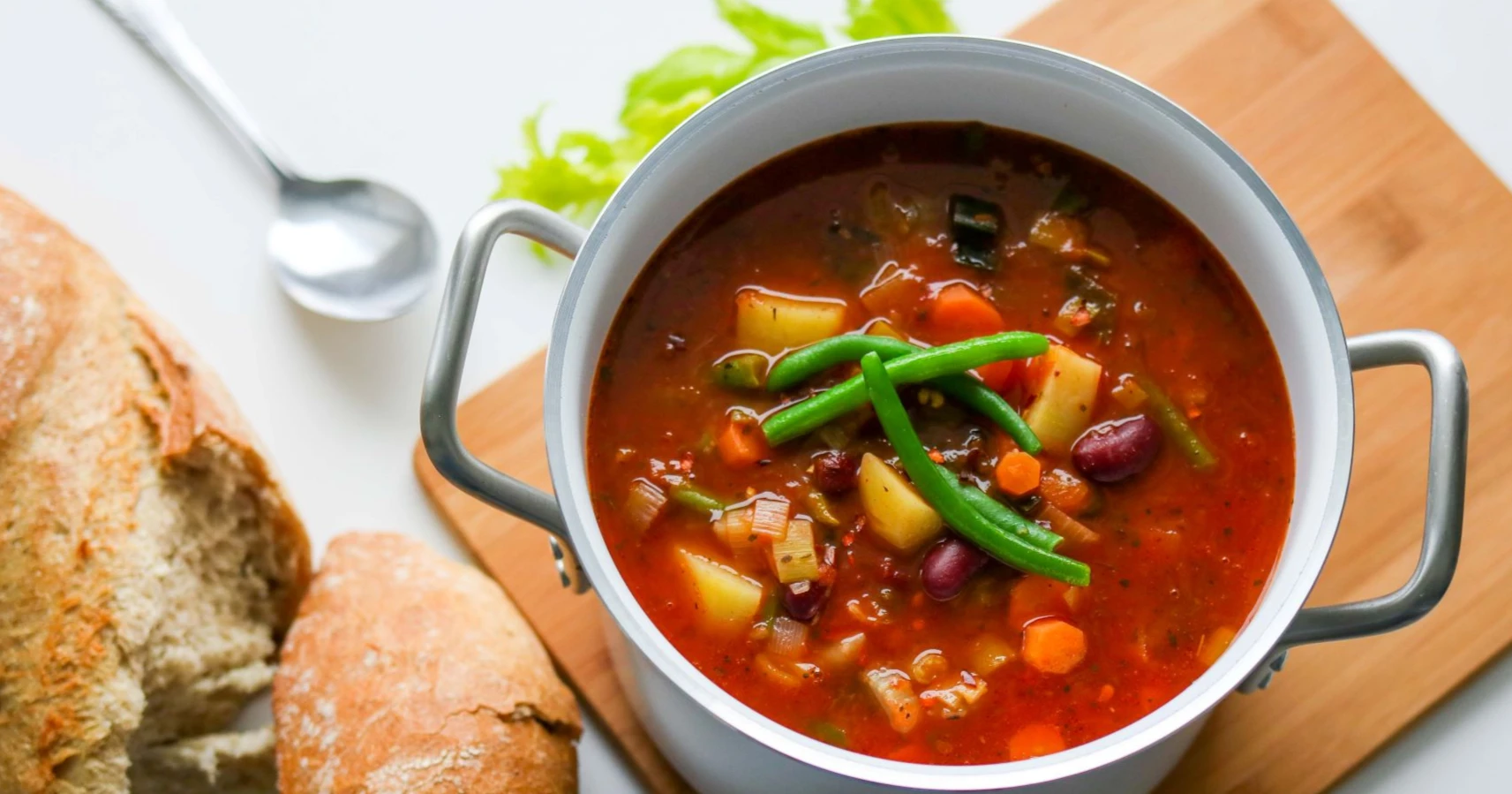 Kasviskeitto kattilassa leivän kera.