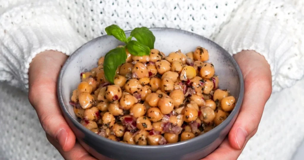 Marinoidut kikherneet kulhossa, jota ojennetaan tarjolle.