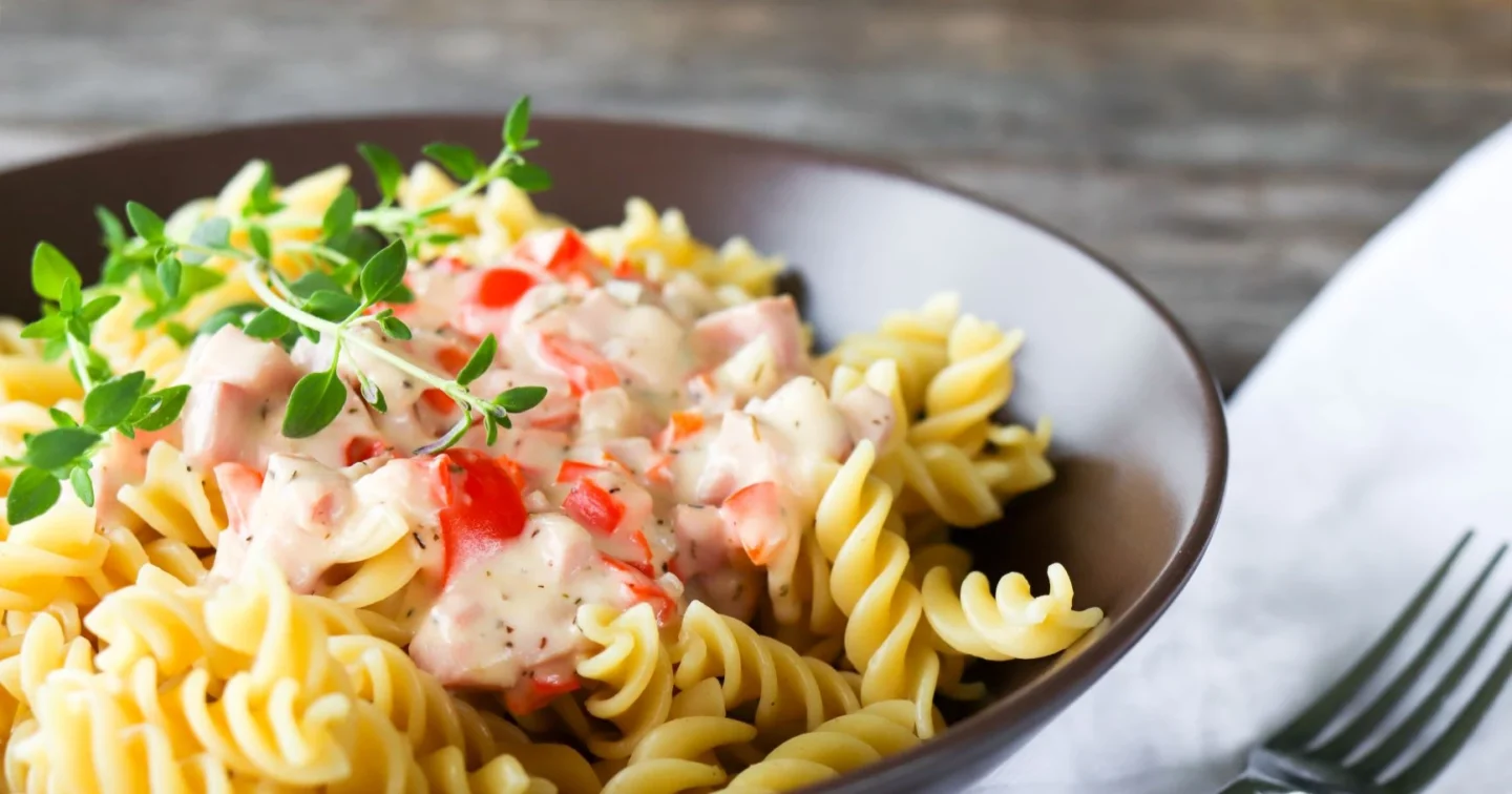 Kinkkukastike pastan päällä lautasella.