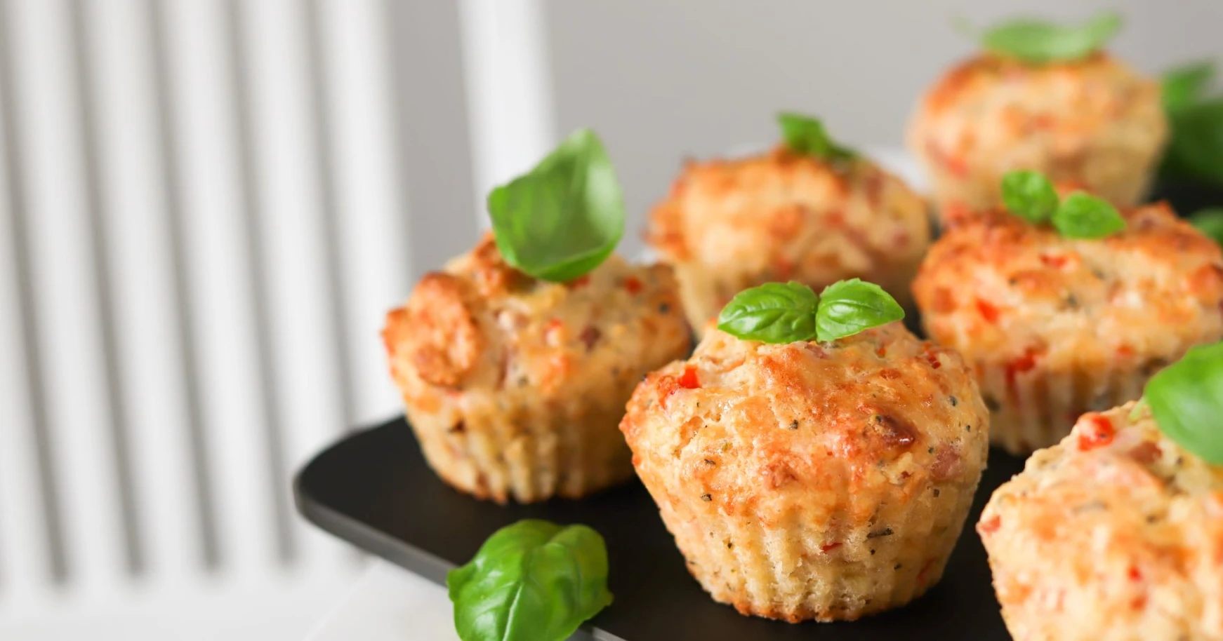 Kinkkumuffinit leikkuulaudalla basilikalla koristeltuna.