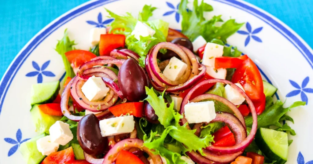 Kreikkalainen salaatti sinisellä värillä kuvioidulla lautasella.