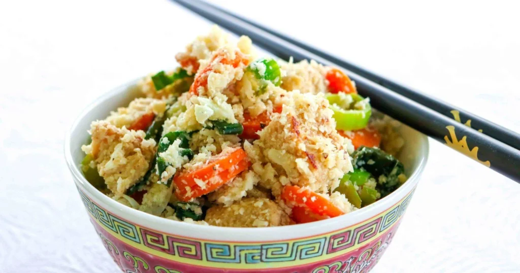 Värikäs kukkakaalista tehty wokki aasialaiseen tapaan kuvioidussa kulhossa.