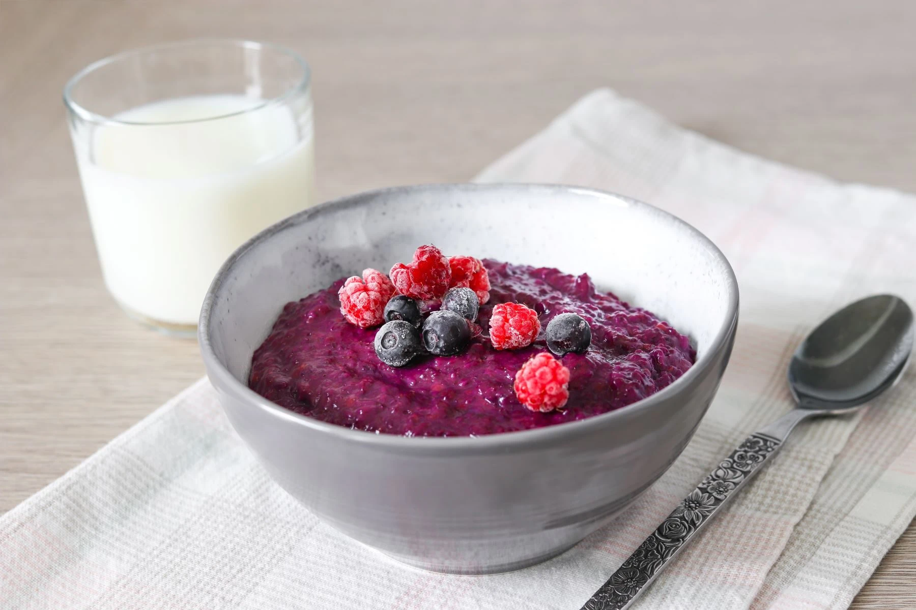 Kuningatarpuuro pienessä kulhossa jäisillä mustikoilla ja vadelmilla koristeltuna.