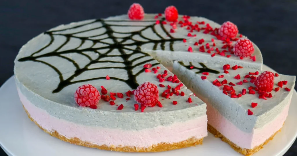 Lakritsi-vadelmajuustokakku, jonka pinnalle on tehty halloweeniin sopiva musta hämähäkin seitti.