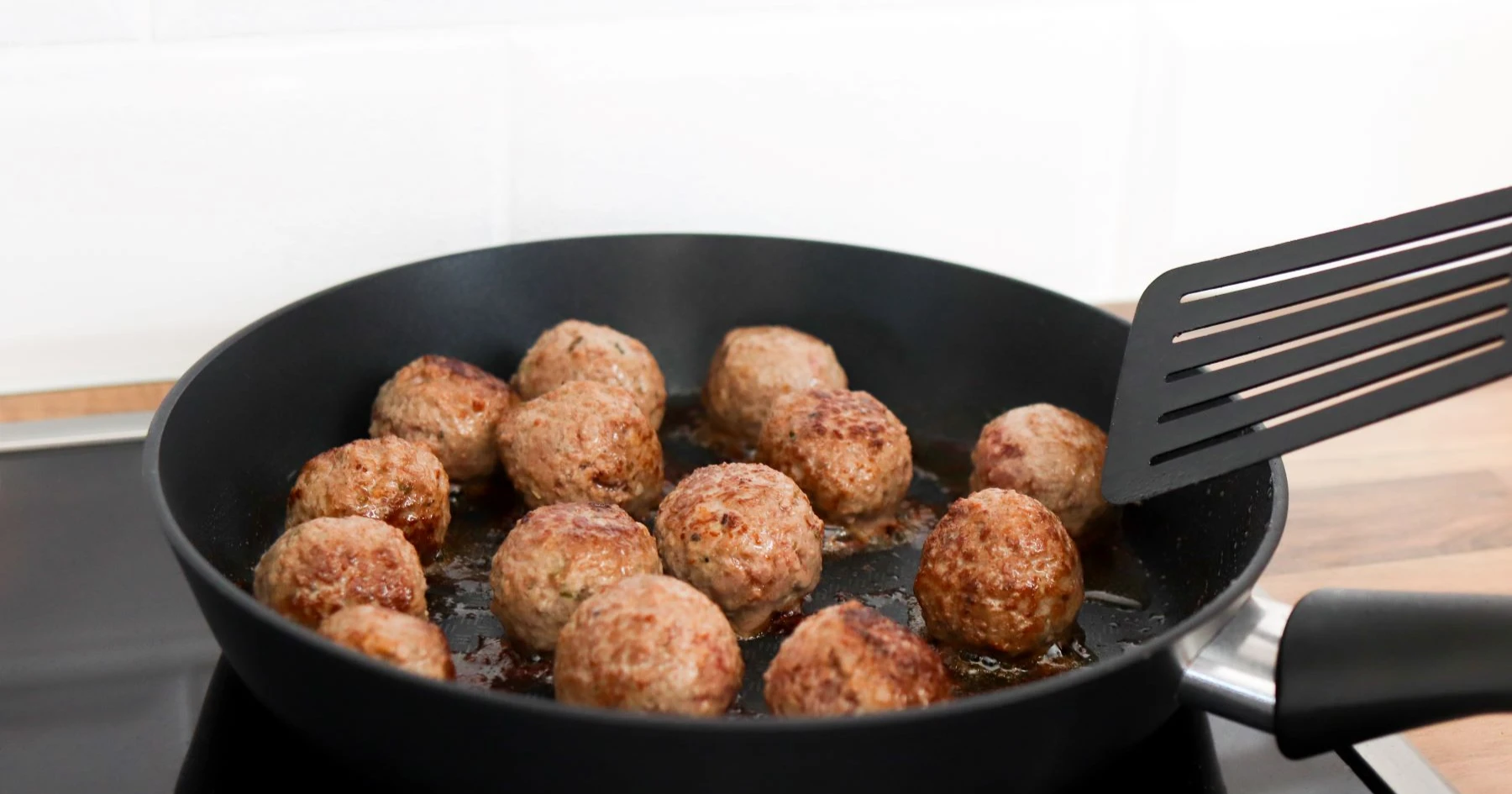 Gluteenittomia lihapullia mustalla paistinpannulla.