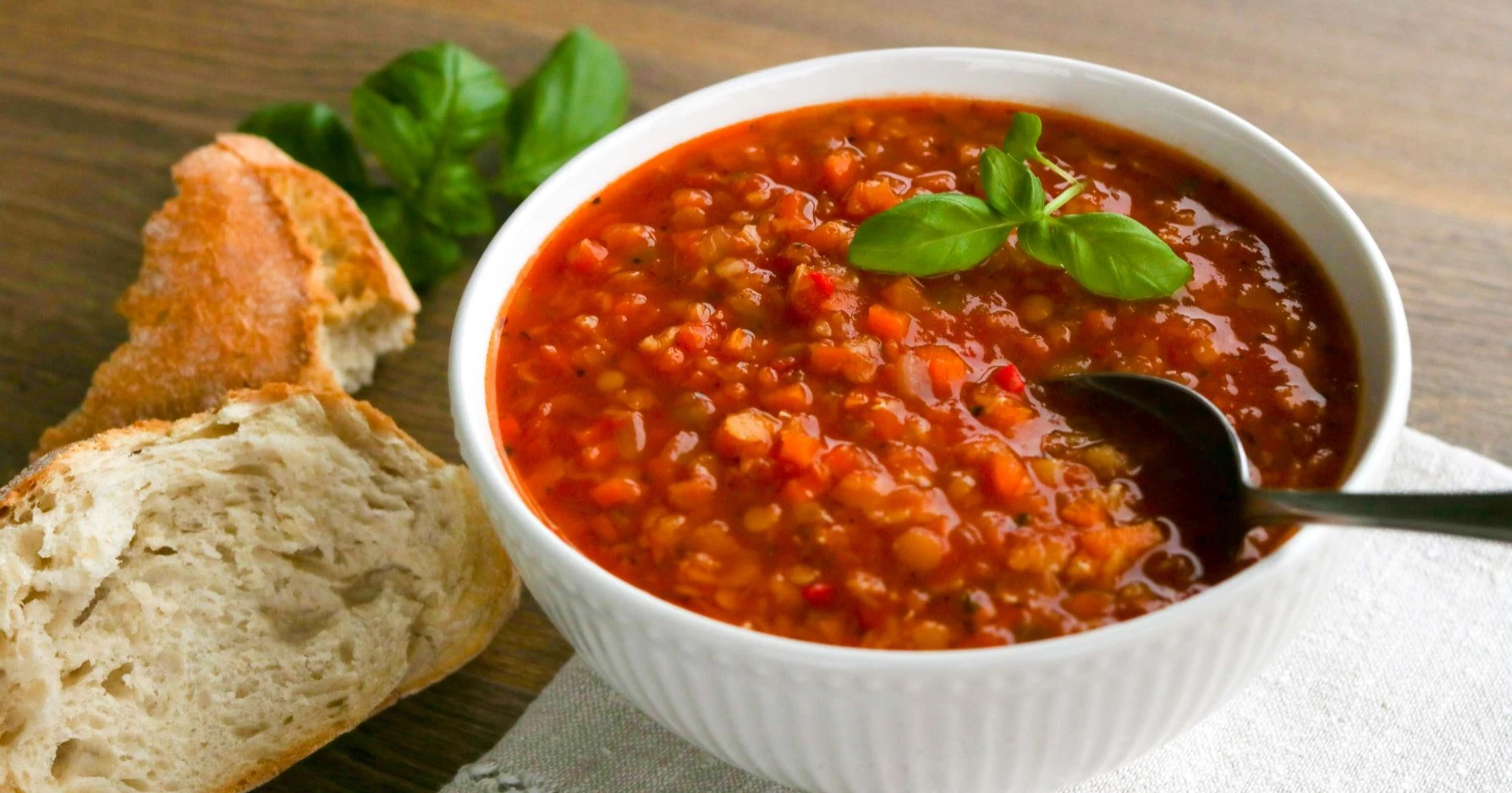 Linssikeitto valkoisessa kulhossa vaalean leivän kanssa.