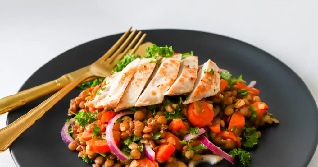 Broileri-linssisalaatti mustalla lautasella.