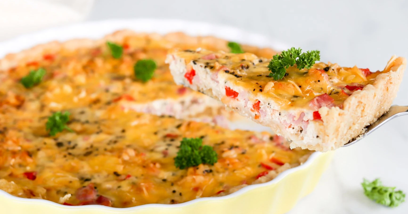 Maidoton suolainen piirakka, josta on leikattu pala kakkulapiolla.