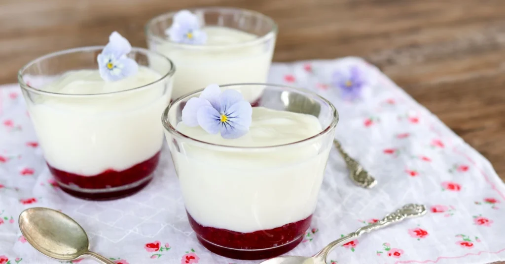 Maitokiisseli pienissä laseissa vadelmahillon kanssa.