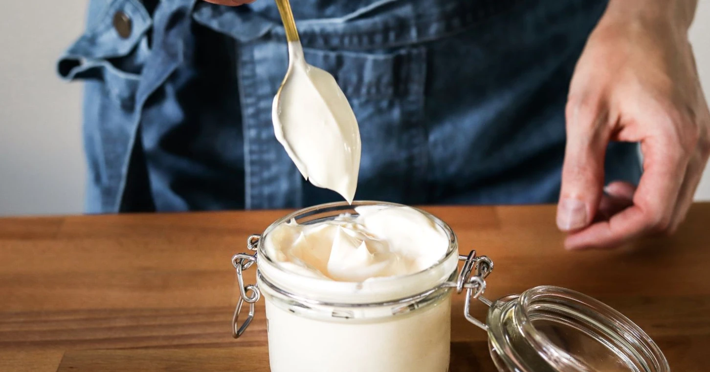 Majoneesi lasisessa purkissa puisen tason päällä.