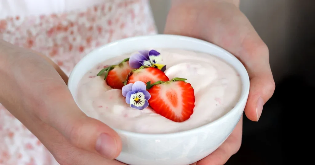 Mansikkarahka kulhossa tuoreilla mansikoilla koristeltuna.