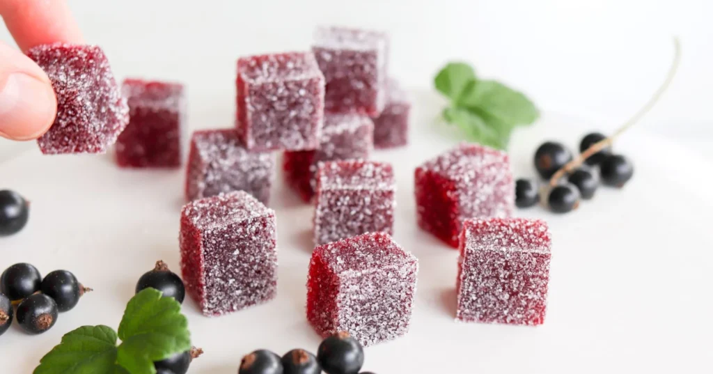 Marmeladeja ja mustaherukoita valkoisella pöydällä.