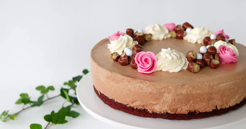 Mokkakakku, joka on koristeltu muun muassa vaaleanpunaisilla sokerimassaruusuilla.