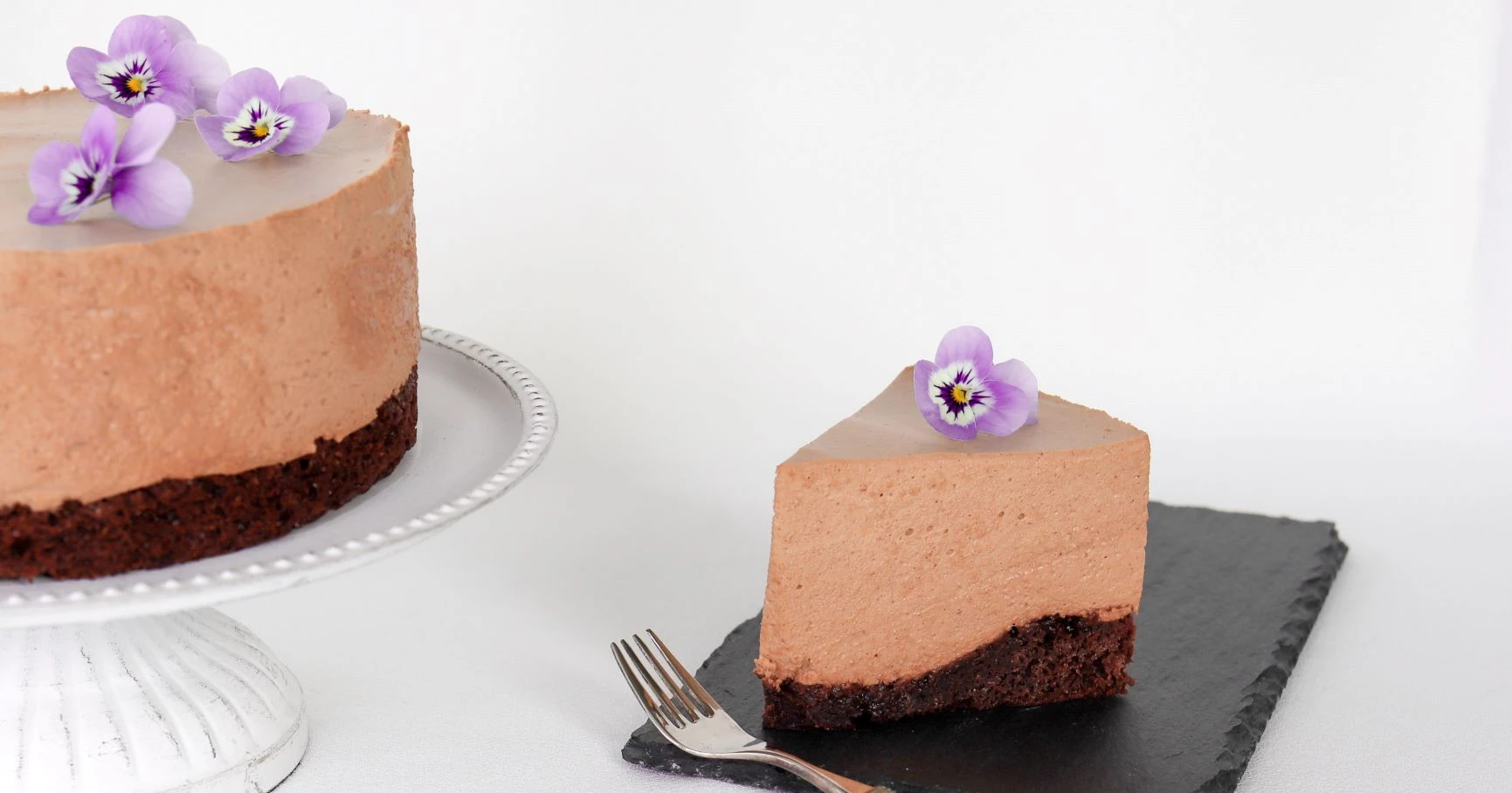 Gluteeniton mokka-suklaakakku, jonka päällä on violetteja orvokkeja.