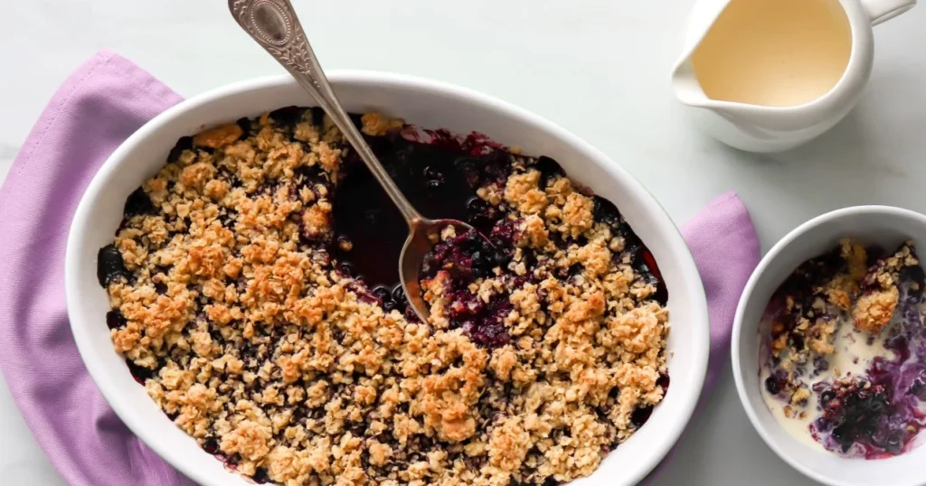 Mustikkapaistos, jota syödään kulhosta vaniljakastikkeen kanssa.