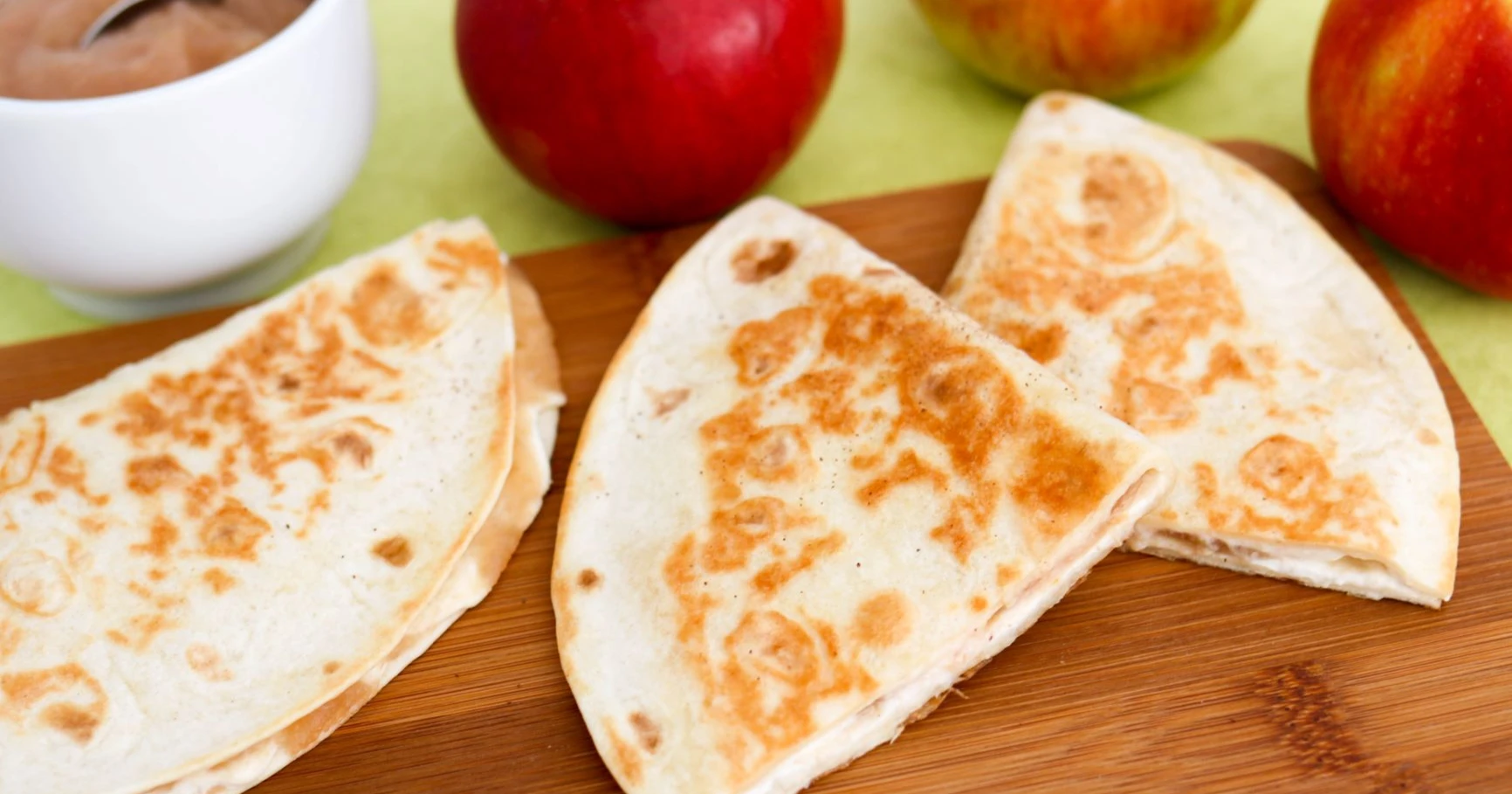 Omena-quesadillat puisen leikkuulaudan päällä.