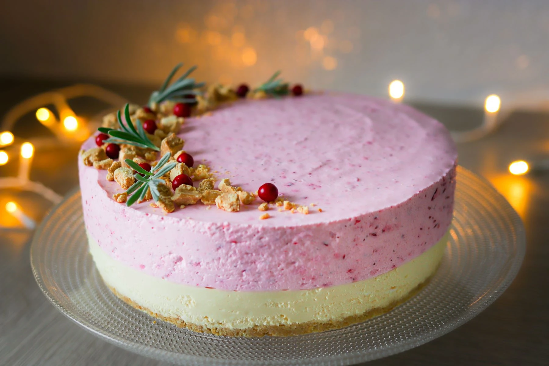 Kahden kerroksen juustokakku, jossa on paahdettua valkosuklaata ja tuoreita puolukoita pinnalla.