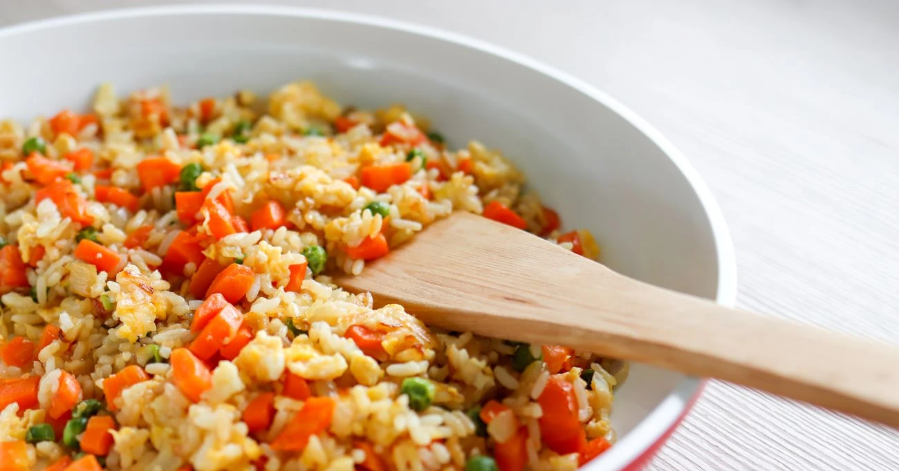 Paistettu riisi, jota sekoitetaan pannulla puisella lastalla.
