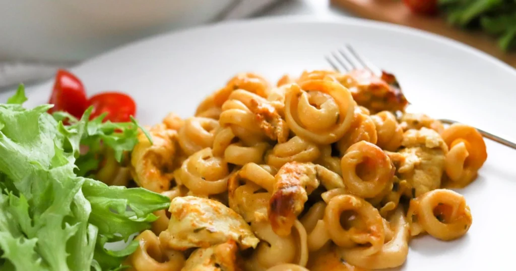 Palermon pasta valkoisella lautasella raikkaan salaatin kanssa.