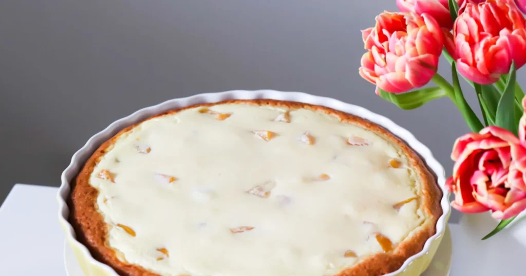 Persikka-rahkapiirakka ja oransseja tulppaaneja.