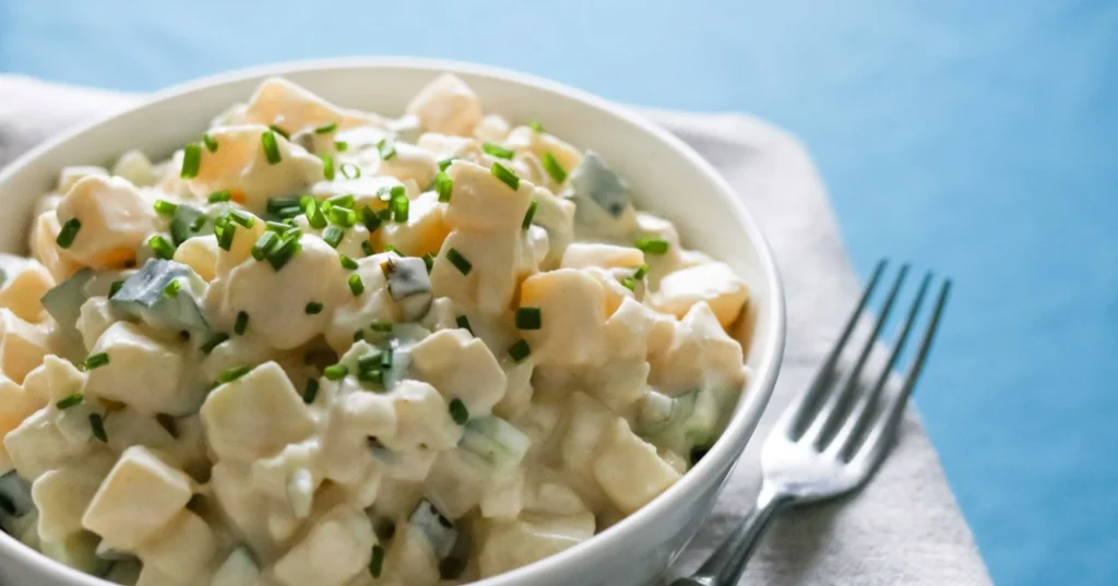 Perunasalaatti valkoisessa tarjoilukulhossa.