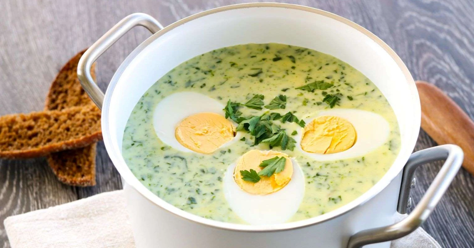 Pinaattikeitto halkaistun kananmunan kanssa kattilassa.