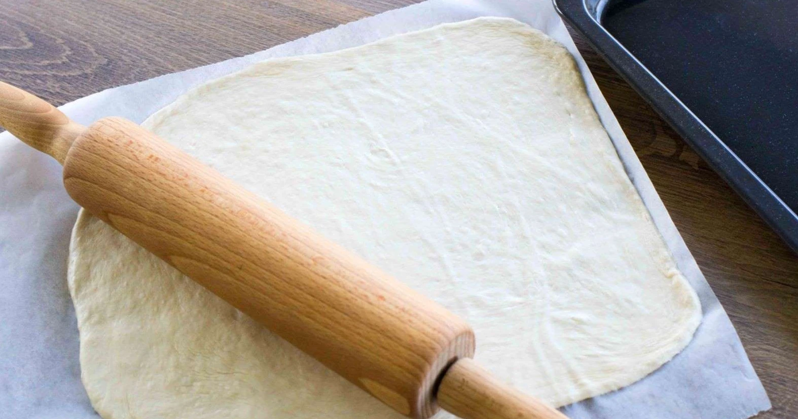 Pizzapohja kaulittuna leivinpaperin päällä.