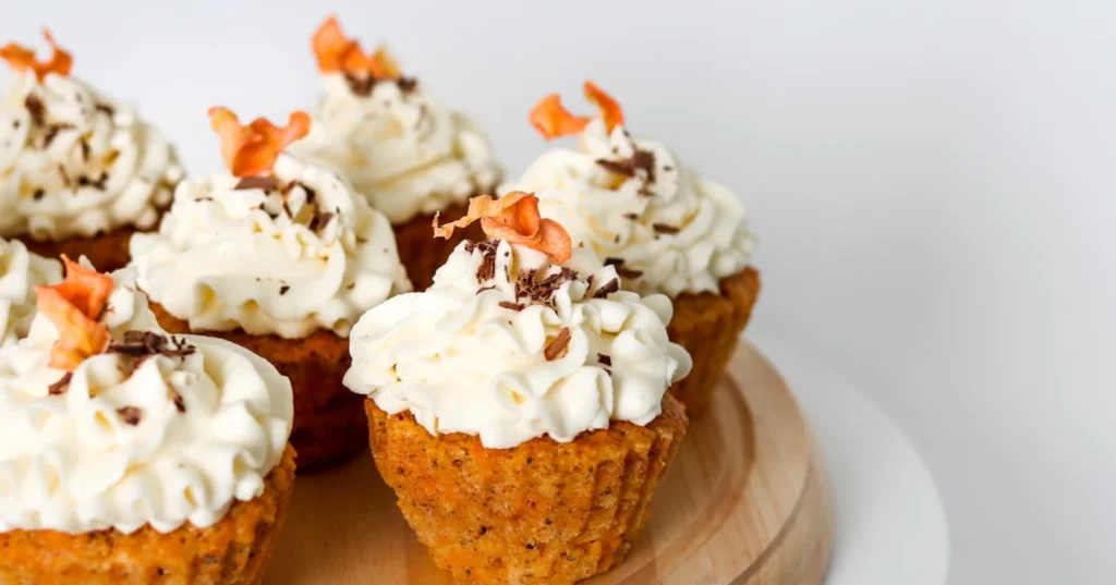 Porkkanamuffinssit tuorejuustokuorrutteella, suklaalla ja kuivatulla porkkanalla koristeltuna.
