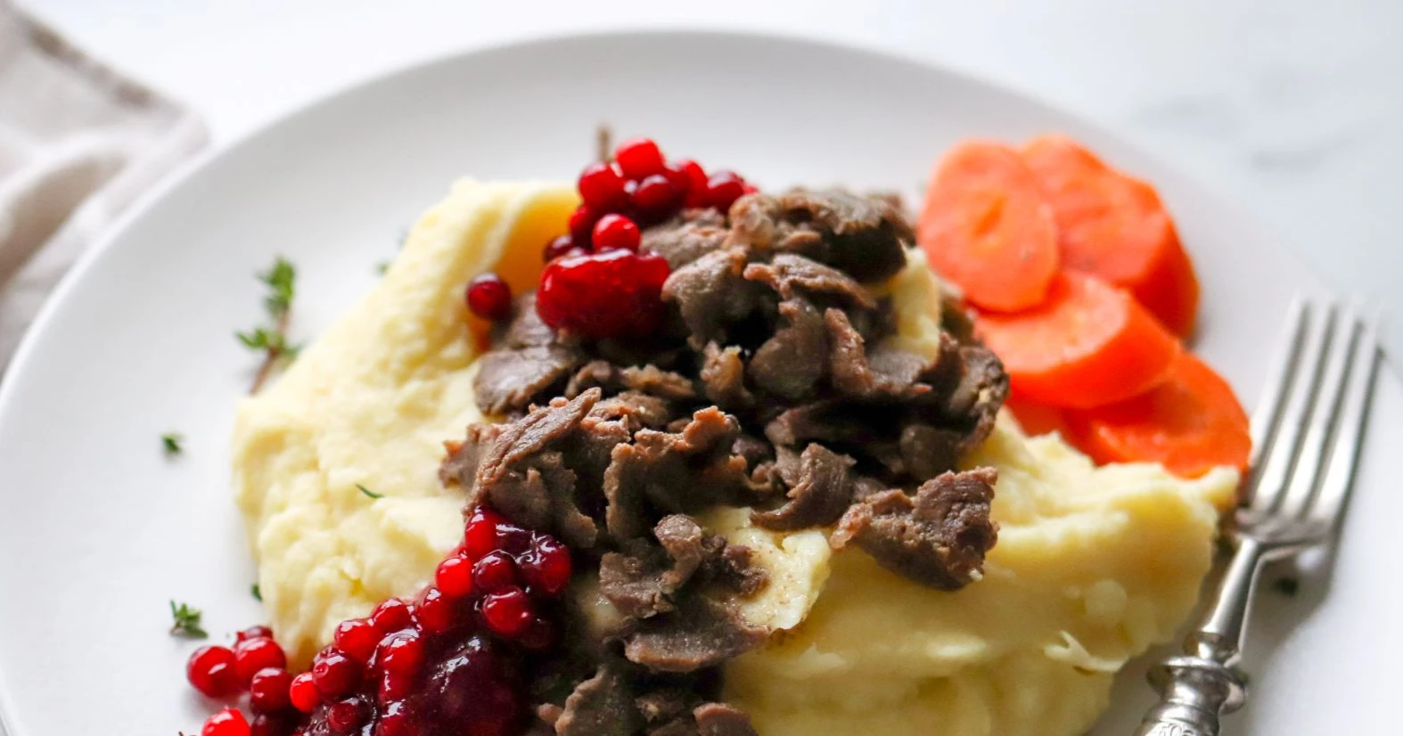 Poronkäristys perunamuusin ja porkkanoiden kera.