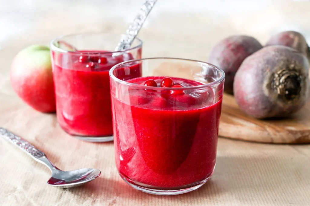 Upean värinen punajuurismoothie kahdessa juomalasissa puolukoilla koristeltuna.