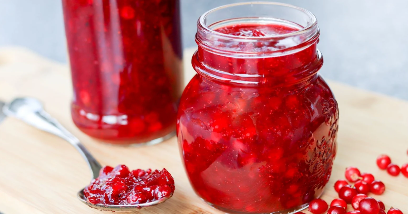 Puolukkahilloa lasipurkissa ja lusikan päällä.