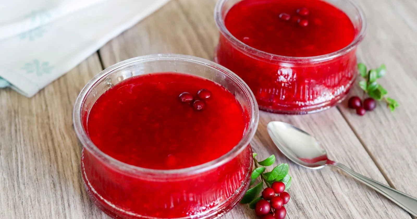 Puolukkakiisseli kulhoissa ja pinnalla tuoreita puolukoita.