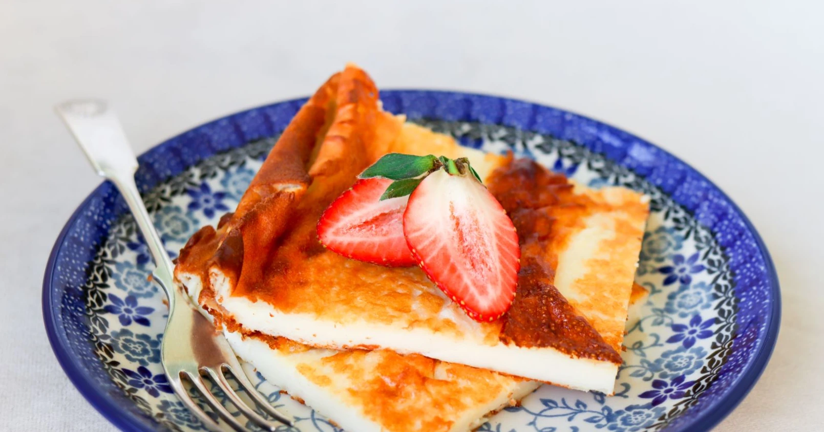 Rahkapannari sinivalkoisella lautasella tuoreiden mansikoiden kanssa