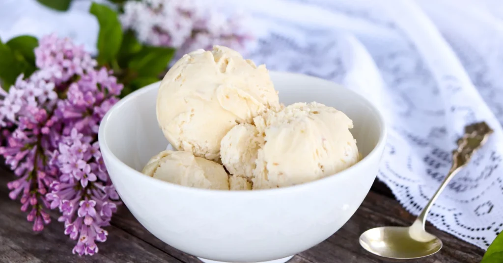 Raparperijäätelö ja syreenin oksia pöydällä.