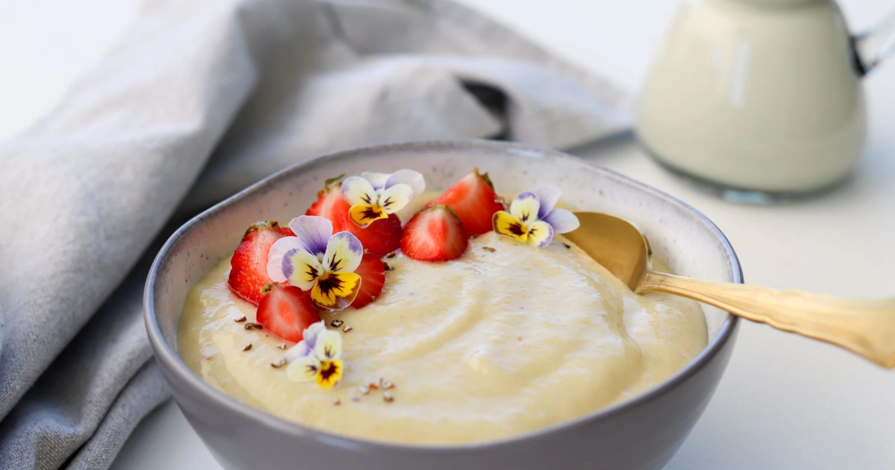 Raparperivispipuuro kulhossa mansikoilla ja orvokeilla koristeltuna.