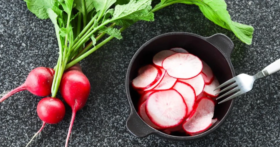 Pikkelöity retiisi ruskeassa kulhossa sekä tuoreita retiisejä naatteineen.