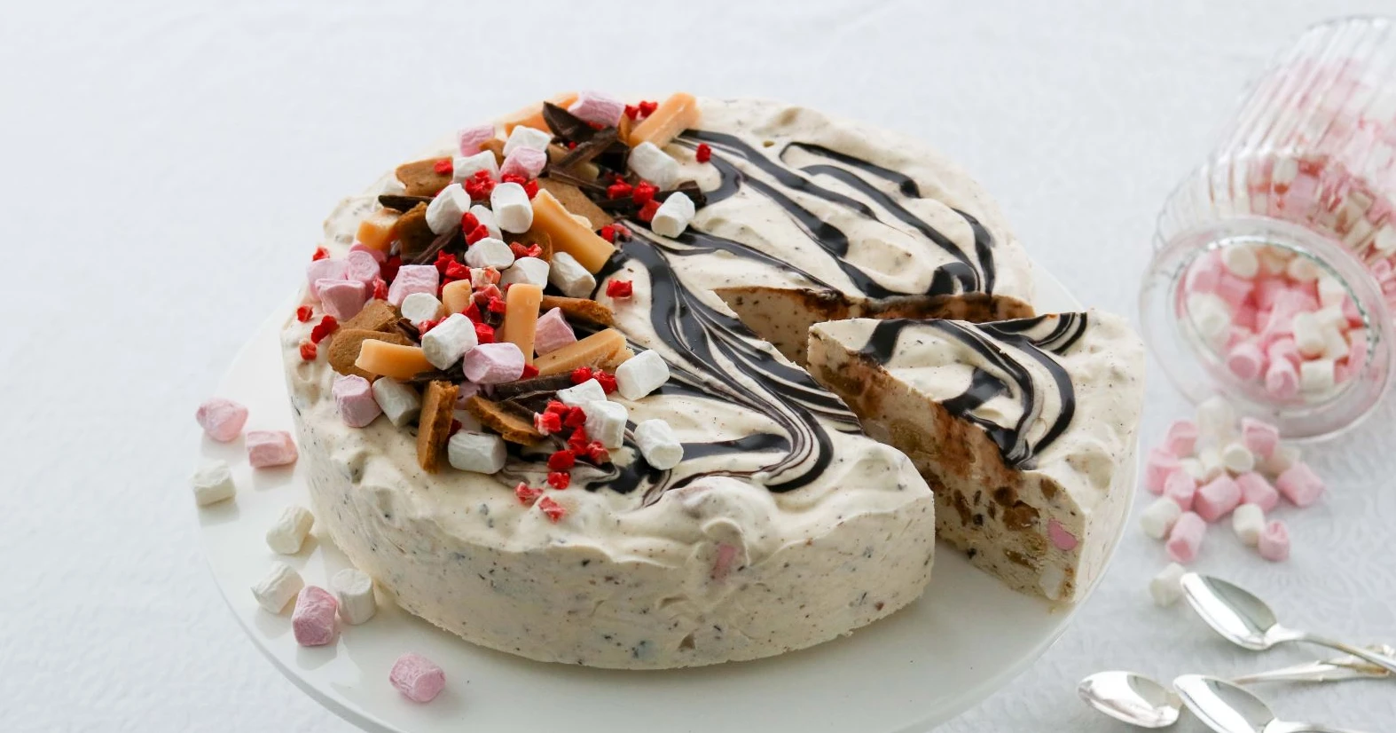 Rocky road -jäädyke, jonka pinta on koristeltu makeisilla ja suklaakastikkeella.