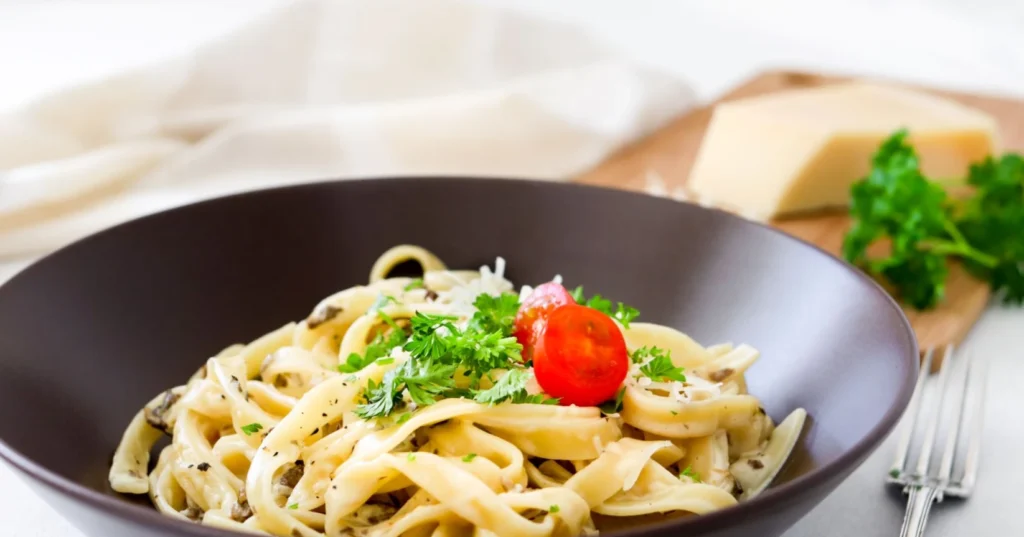 Sienipasta tomaatilla ja persiljalla koristeltuna.