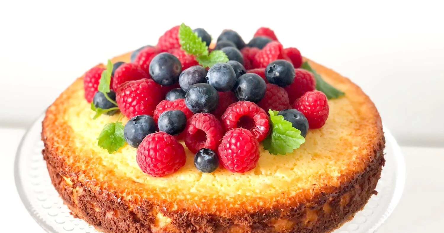Uunissa paistettu sitruunajuustokakku tuoreilla marjoilla koristeltuna.