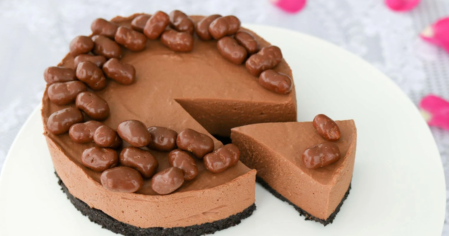 Suklaajuustokakku, joka on tehty ilman liivatetta ja koristeltu rapeilla suklaamakeisilla.