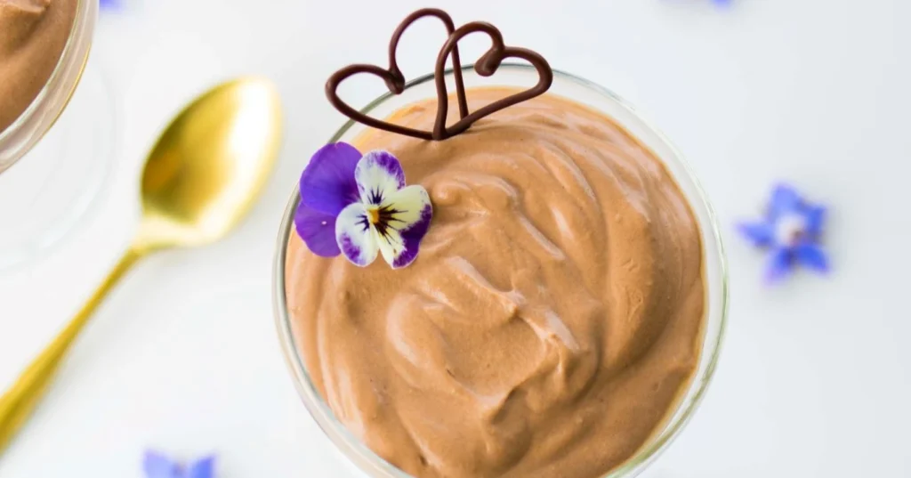 Suklaamousse sinisillä kukilla koristeltuna kulhossa.